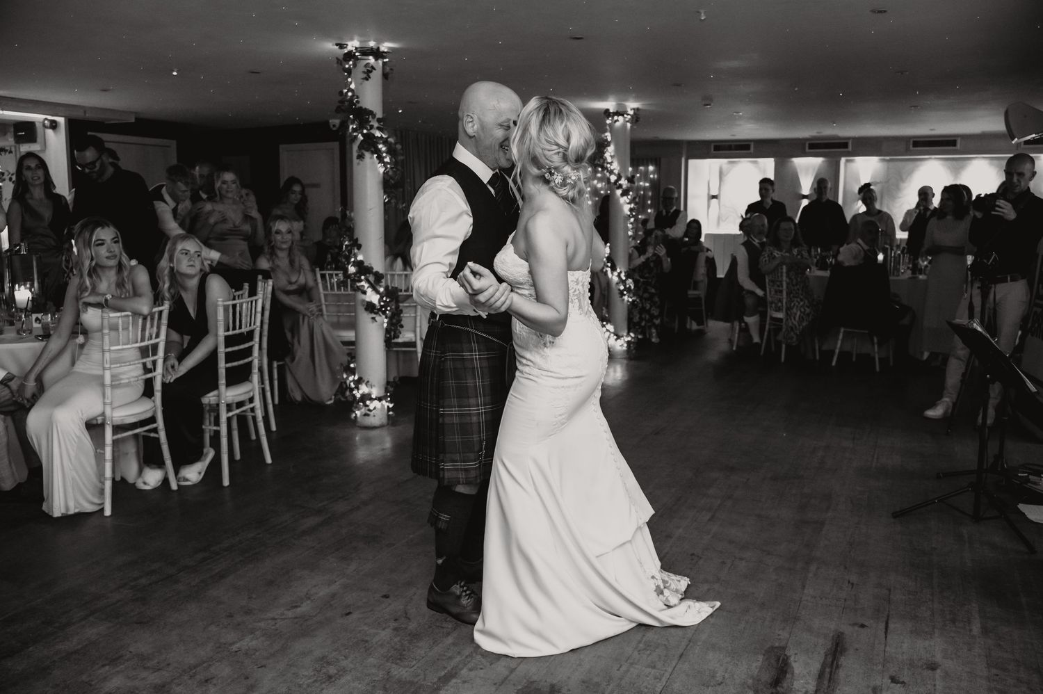 Wedding guests dancing and celebrating on the reception dance floor in black and white.