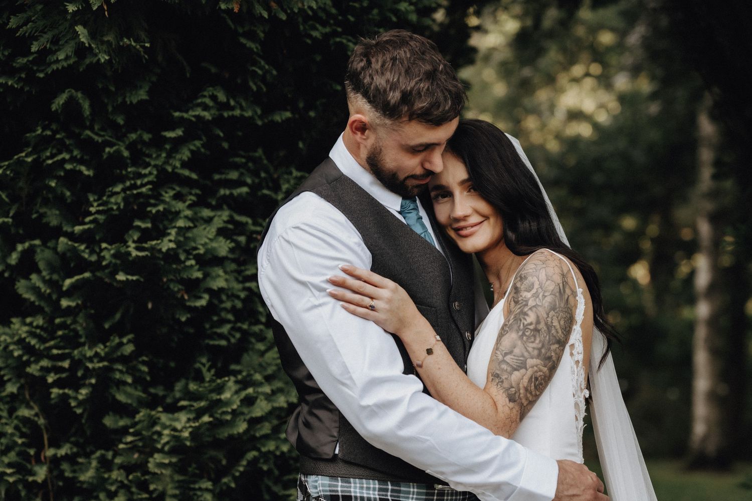 Romantic wedding couple sharing an intimate moment among trees and greenery.