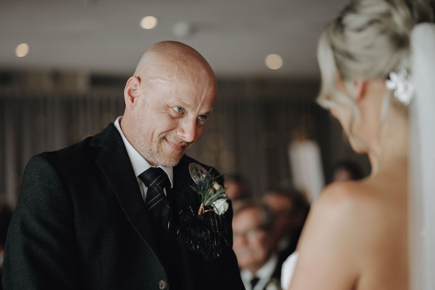 Candid moment during wedding ceremony with elegant indoor lighting.