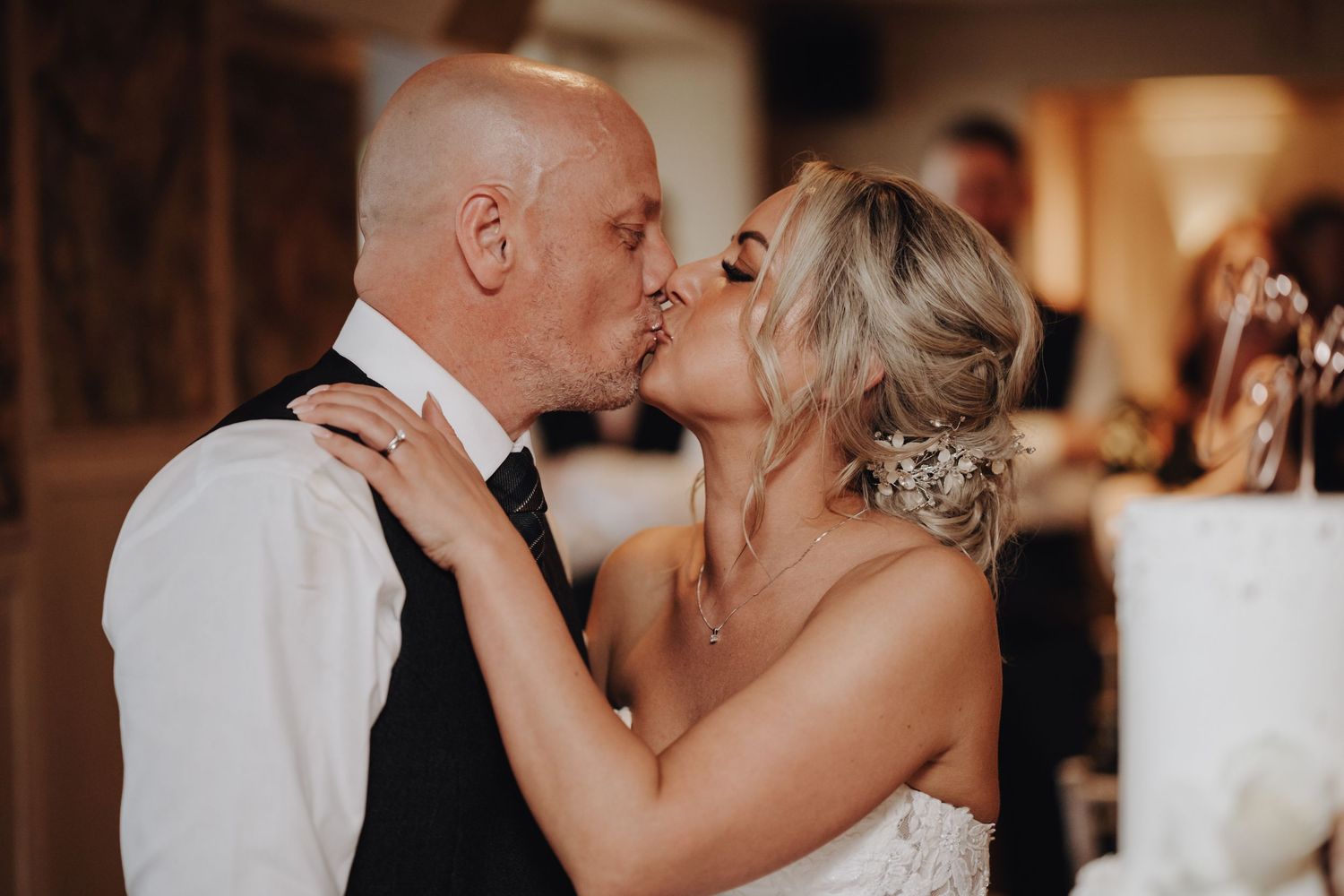 Tender wedding moment captured in warm ambient lighting at reception.