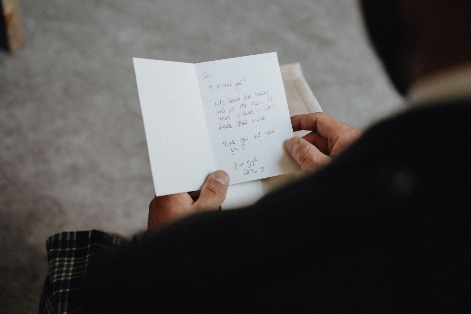 Someone in formal attire reads a handwritten note or letter against a dark background.