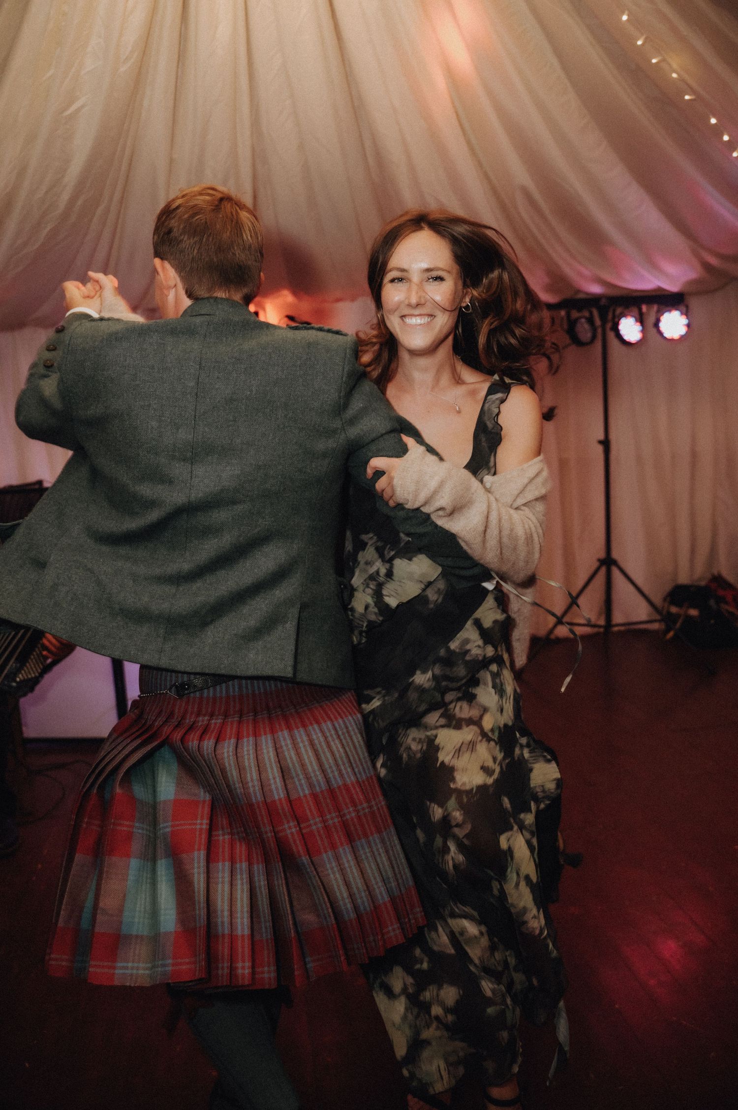 Guests dancing at a Scottish wedding with one wearing a traditional tartan kilt.