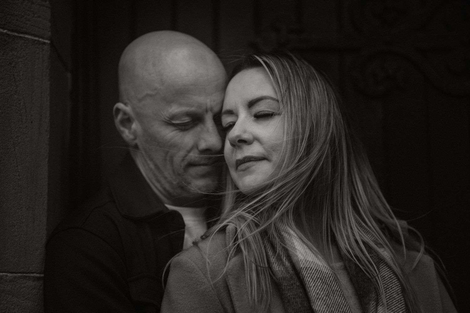 An intimate black and white portrait of a couple sharing a tender moment.