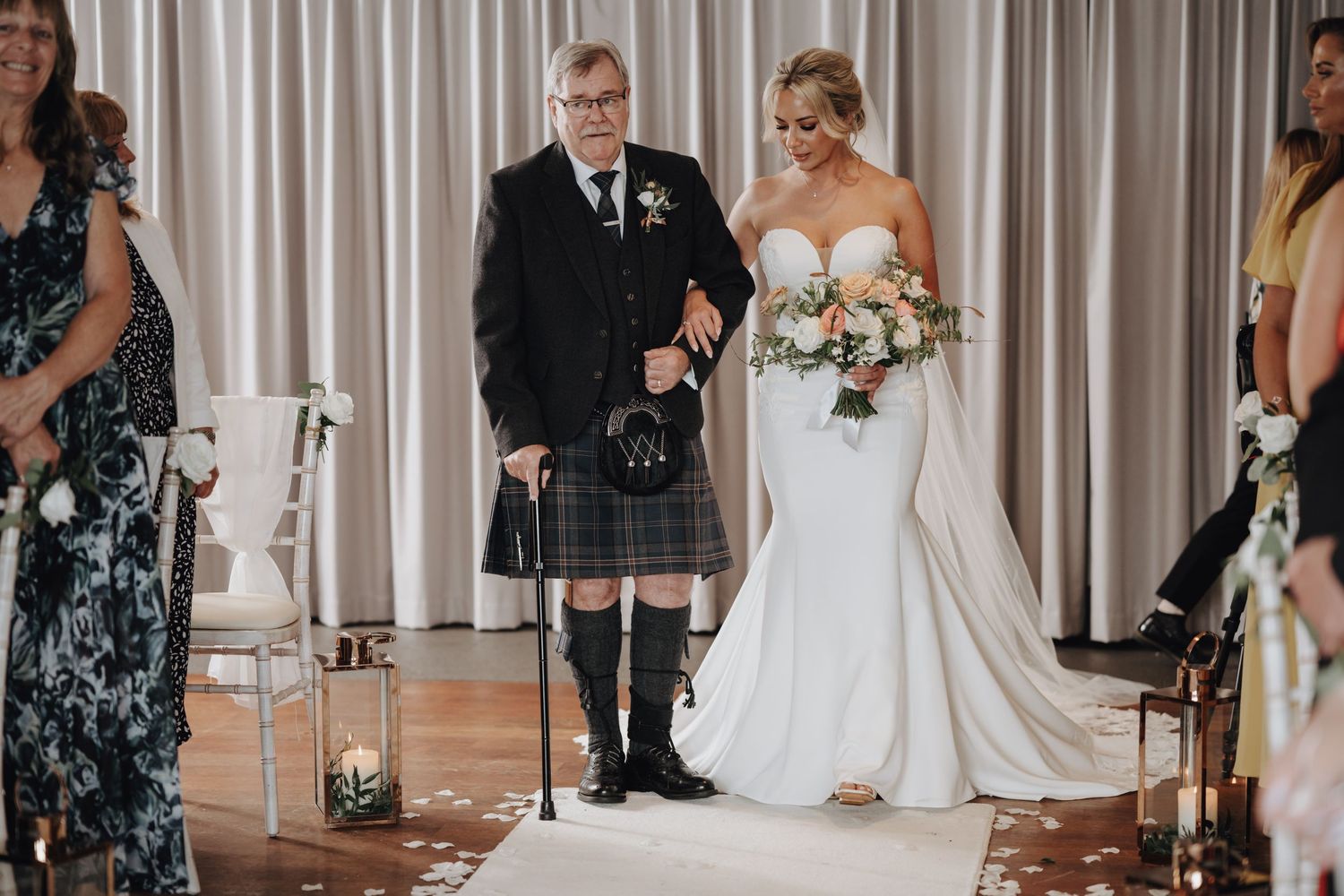 Traditional Scottish wedding ceremony with groom in kilt and bride in fitted white gown.