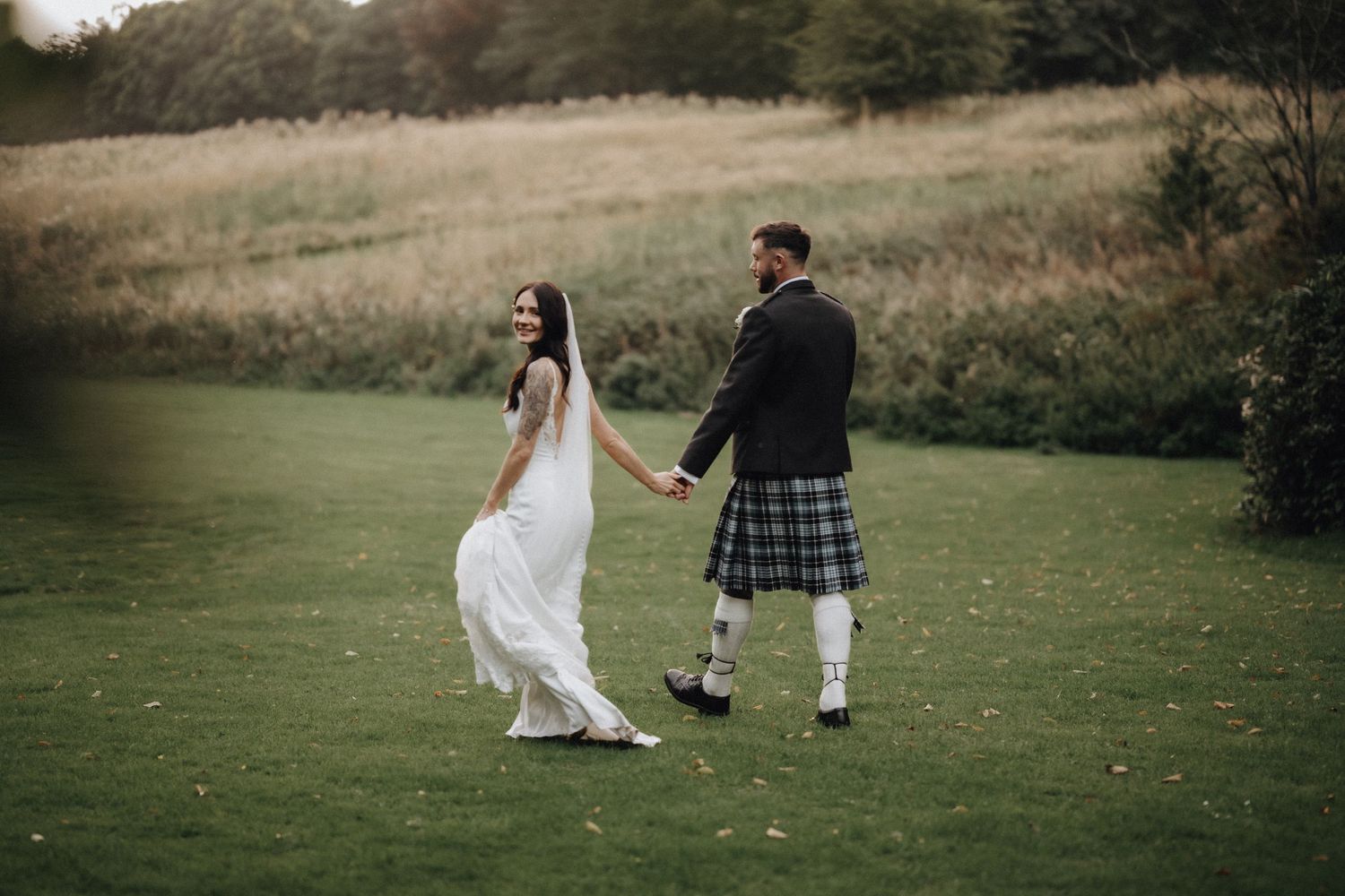 Couple walking through a scenic field during their wedding photoshoot.