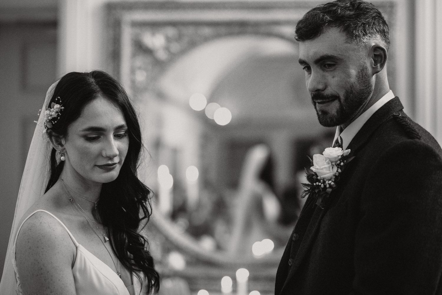 Black and white portrait of bride and groom exchanging intimate glances during their ceremony.