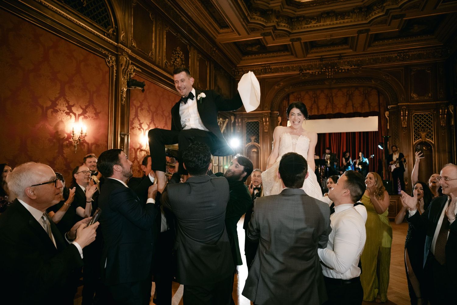 Wedding celebration in an ornate ballroom with guests cheering.