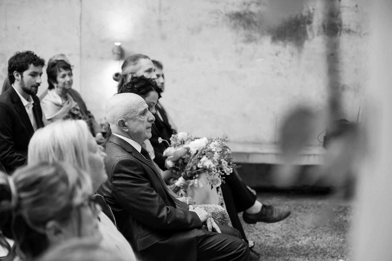 Black and white photo of wedding guests seated outdoors during ceremony.