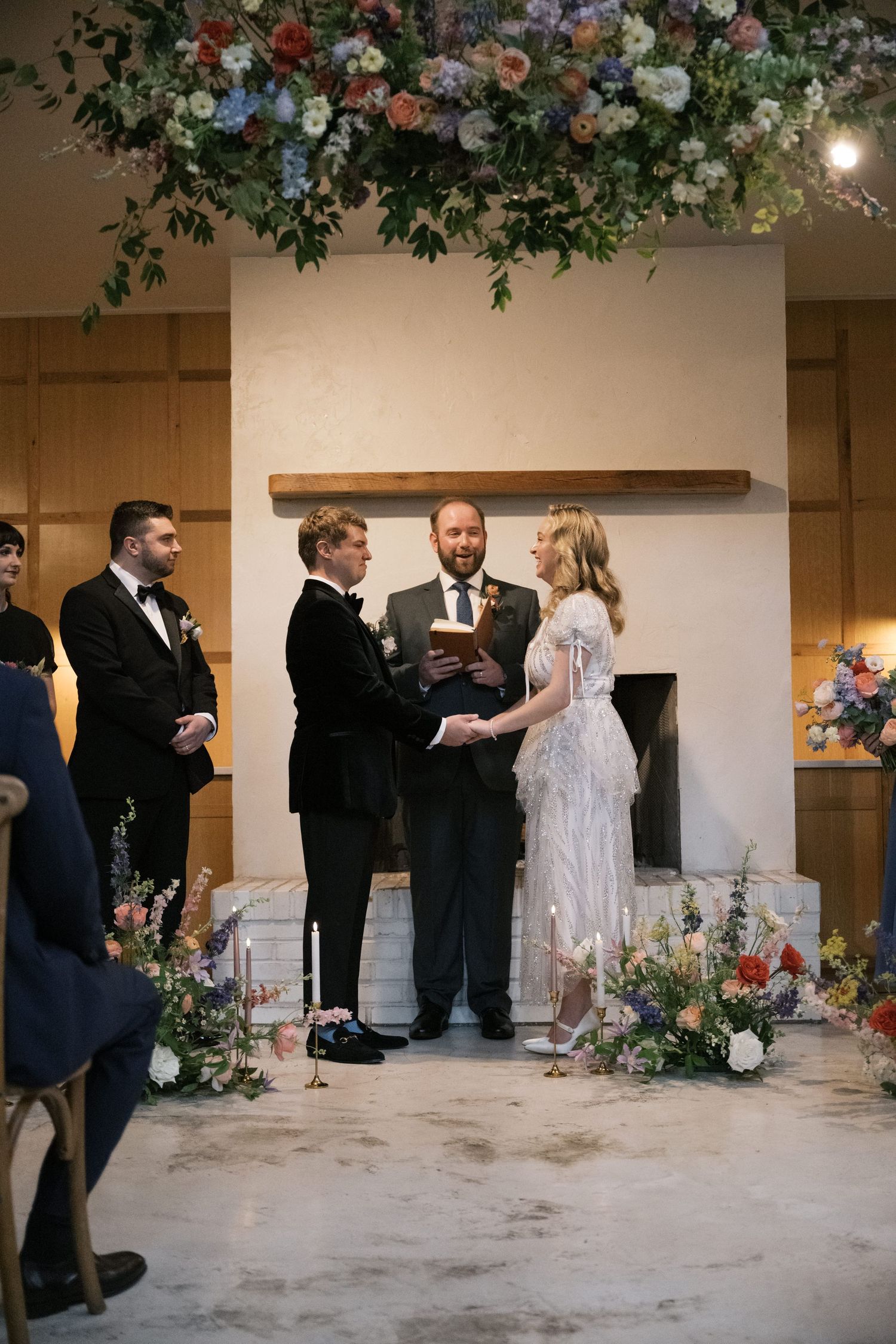 Wedding ceremony setup with floral arch and rustic decor in front of modern fireplace.