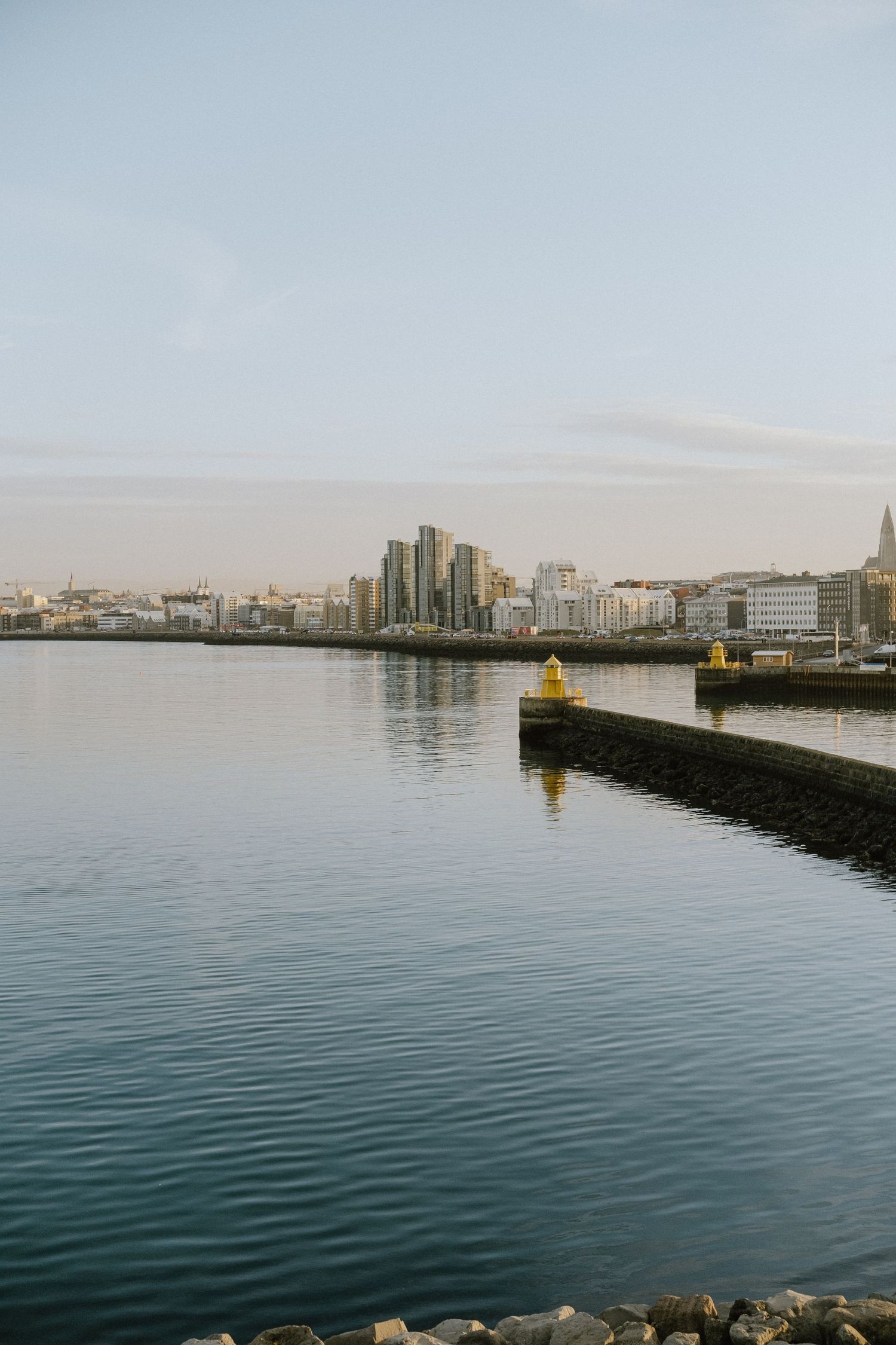 Cityscape view across harbor with yellow buoy and modern buildings on the horizon.