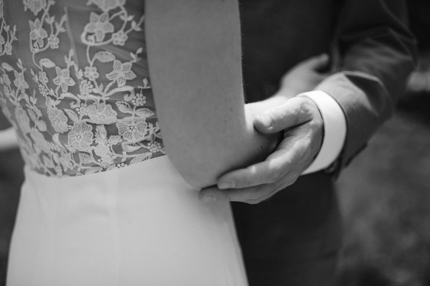 Intimate black and white portrait of newlyweds against an ivy-covered wall.