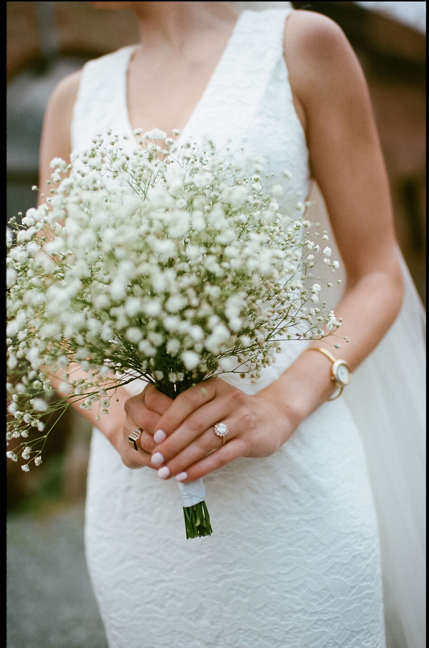 Delicate baby's breath bouquet held by hands in white wedding dress.