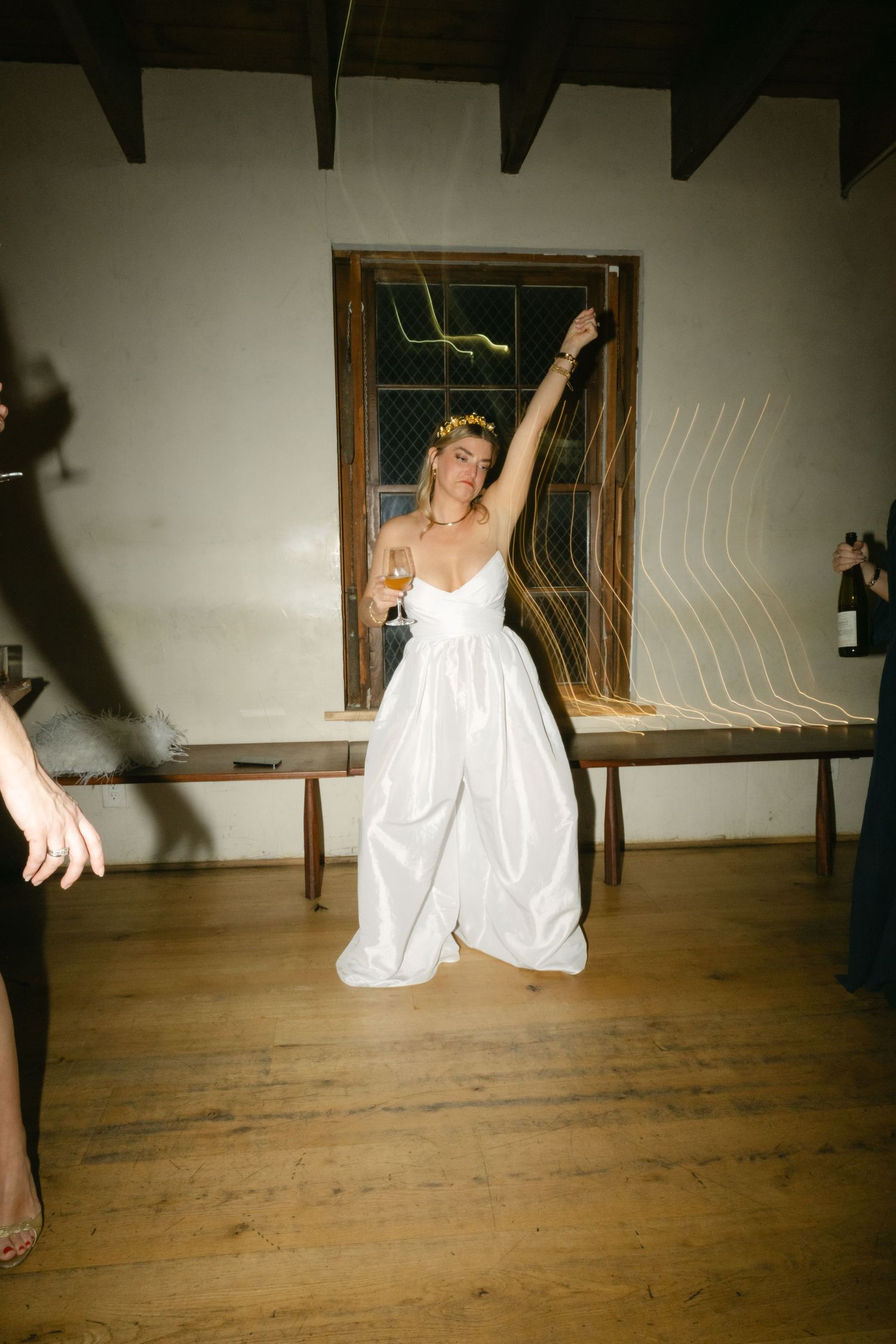 A woman in a white dress dances energetically with her arm raised in celebration.