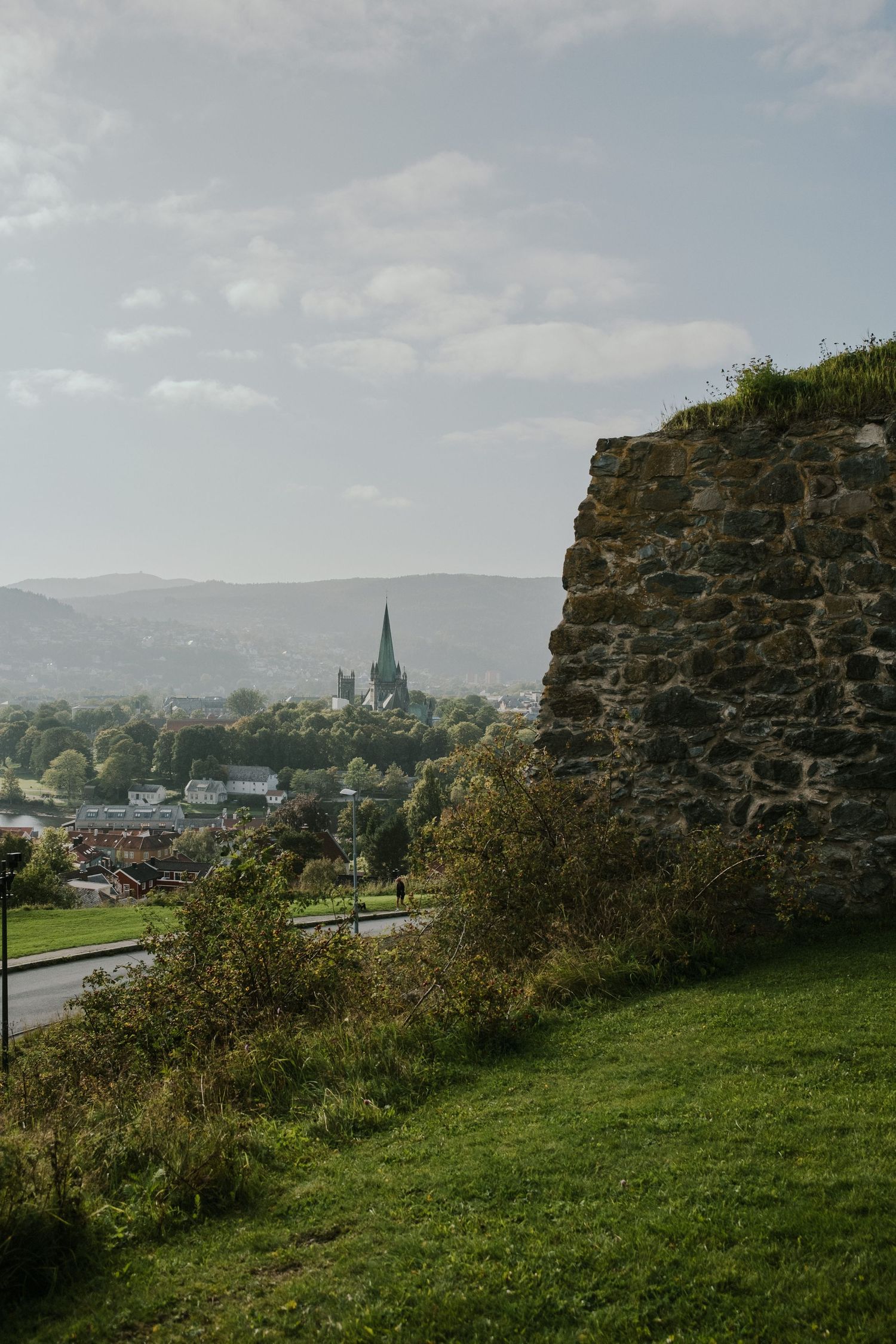 Historic church spire visible through stone ruins overlooking a valley town.