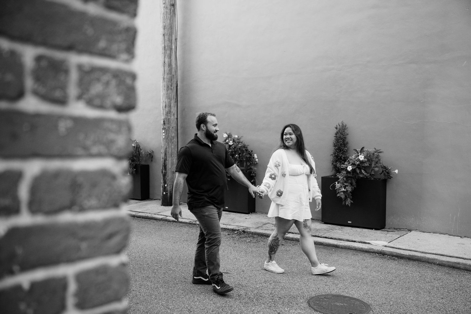 A couple dancing and laughing together on a city street in black and white.