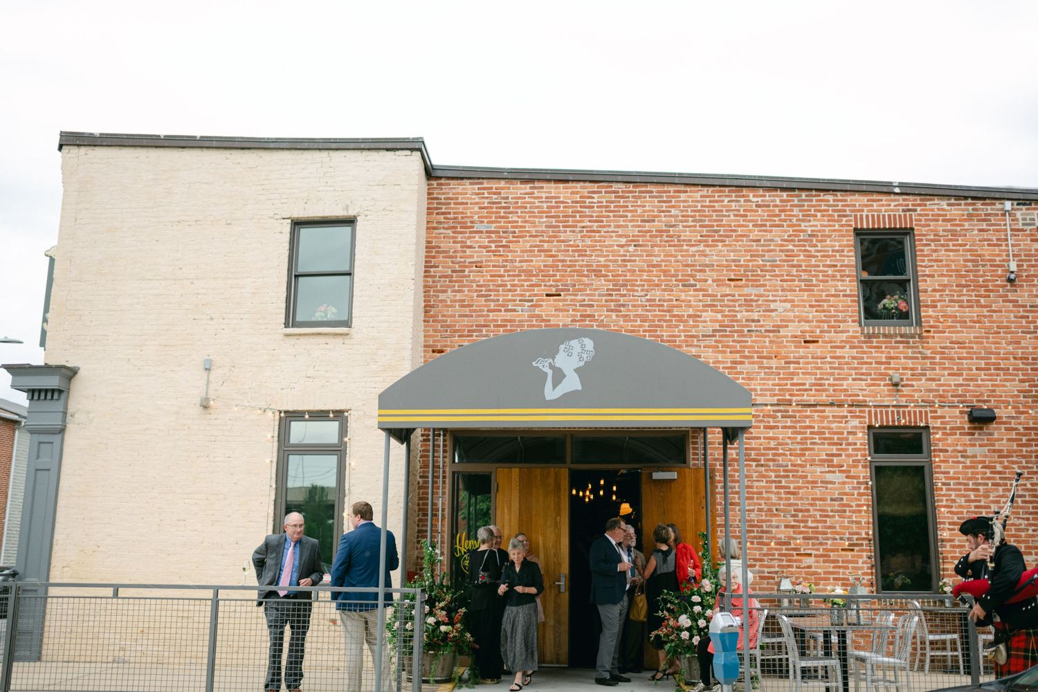 The exterior of a brick building with guests gathered under a dark awning.