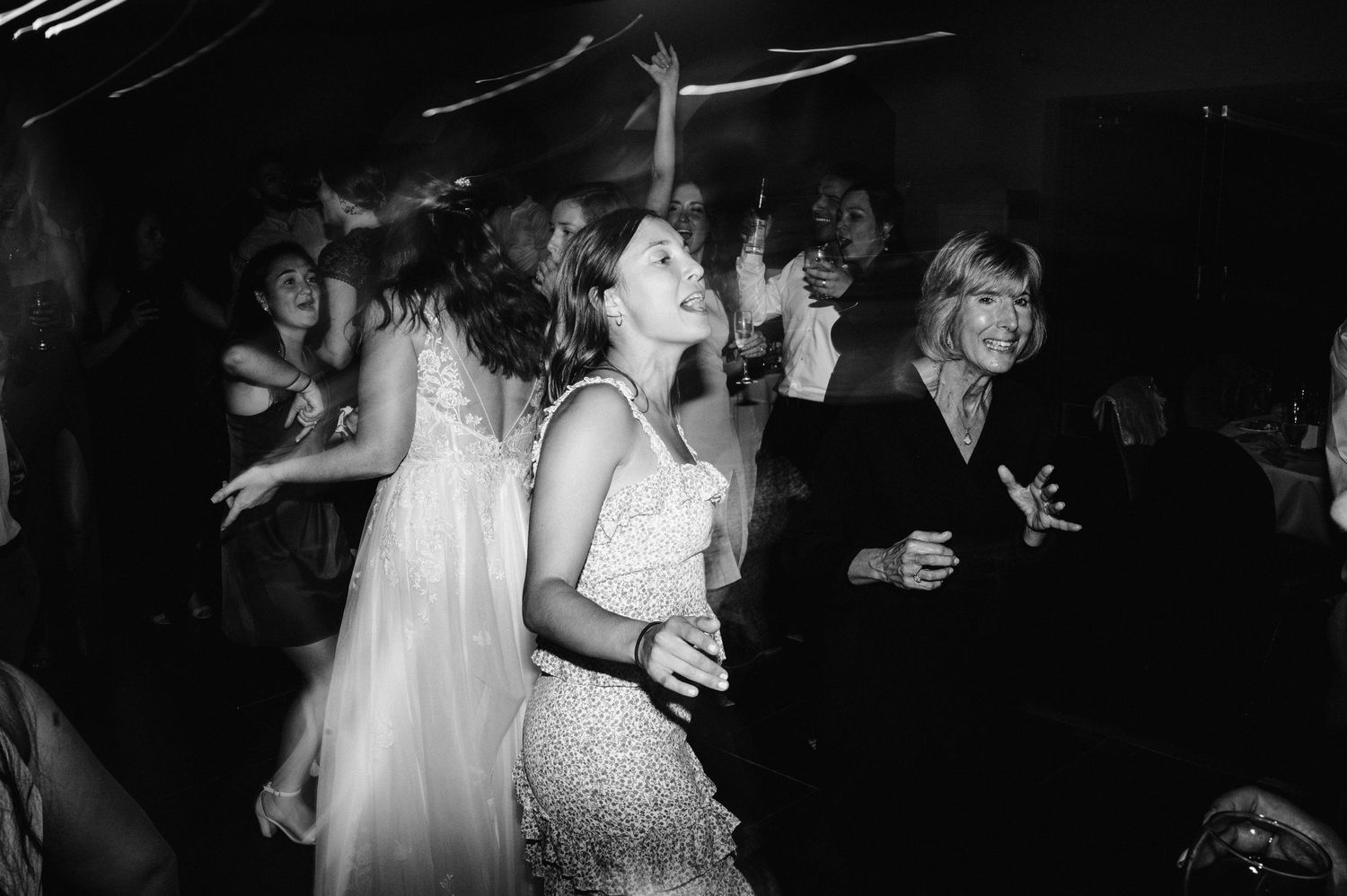 Black and white photo of wedding reception dance party with guests celebrating.