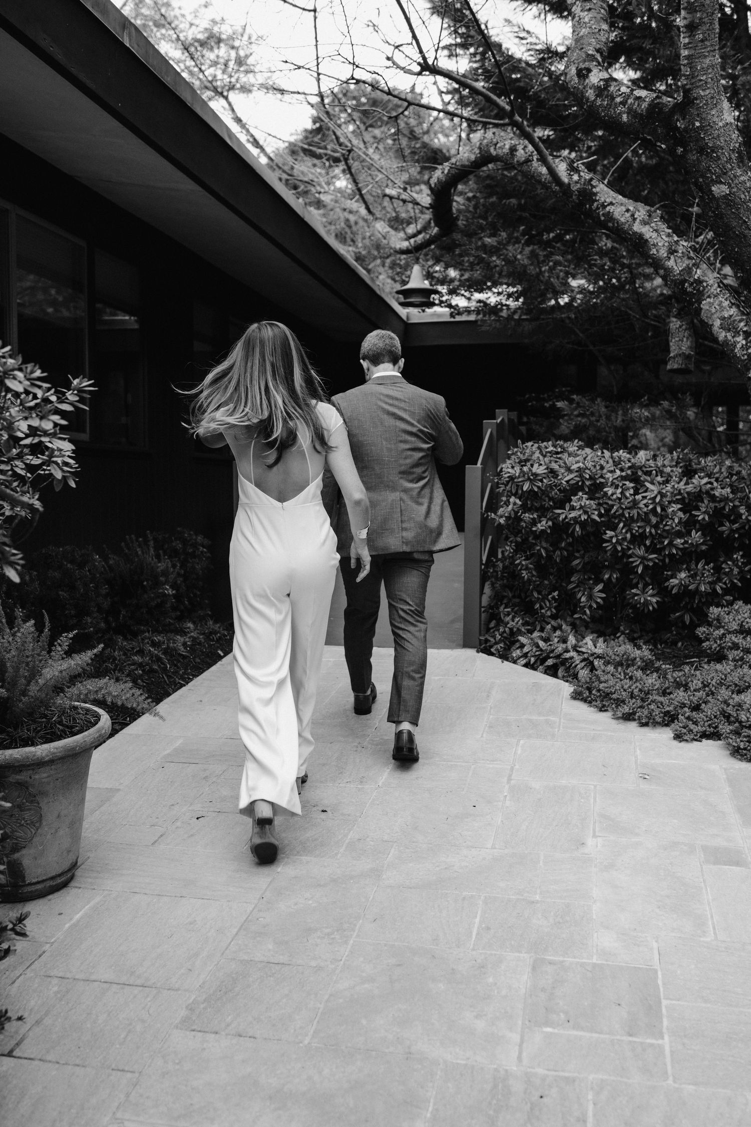 Black and white image of couple walking along stone path at venue.