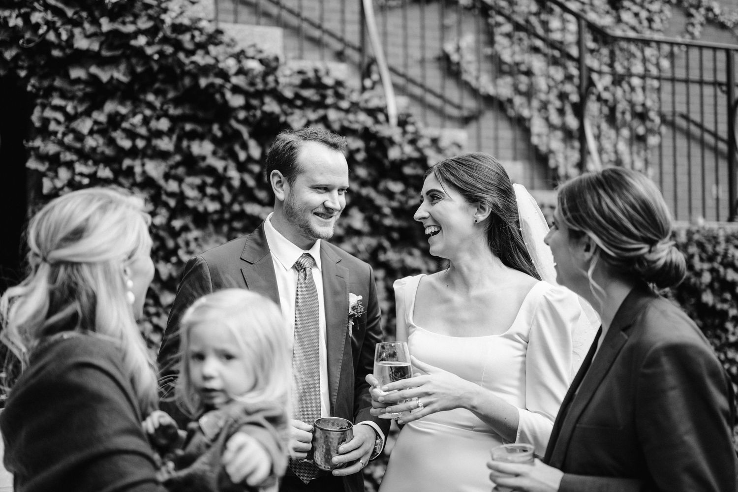 Wedding celebration in a garden setting with ivy-covered walls creating a natural backdrop.