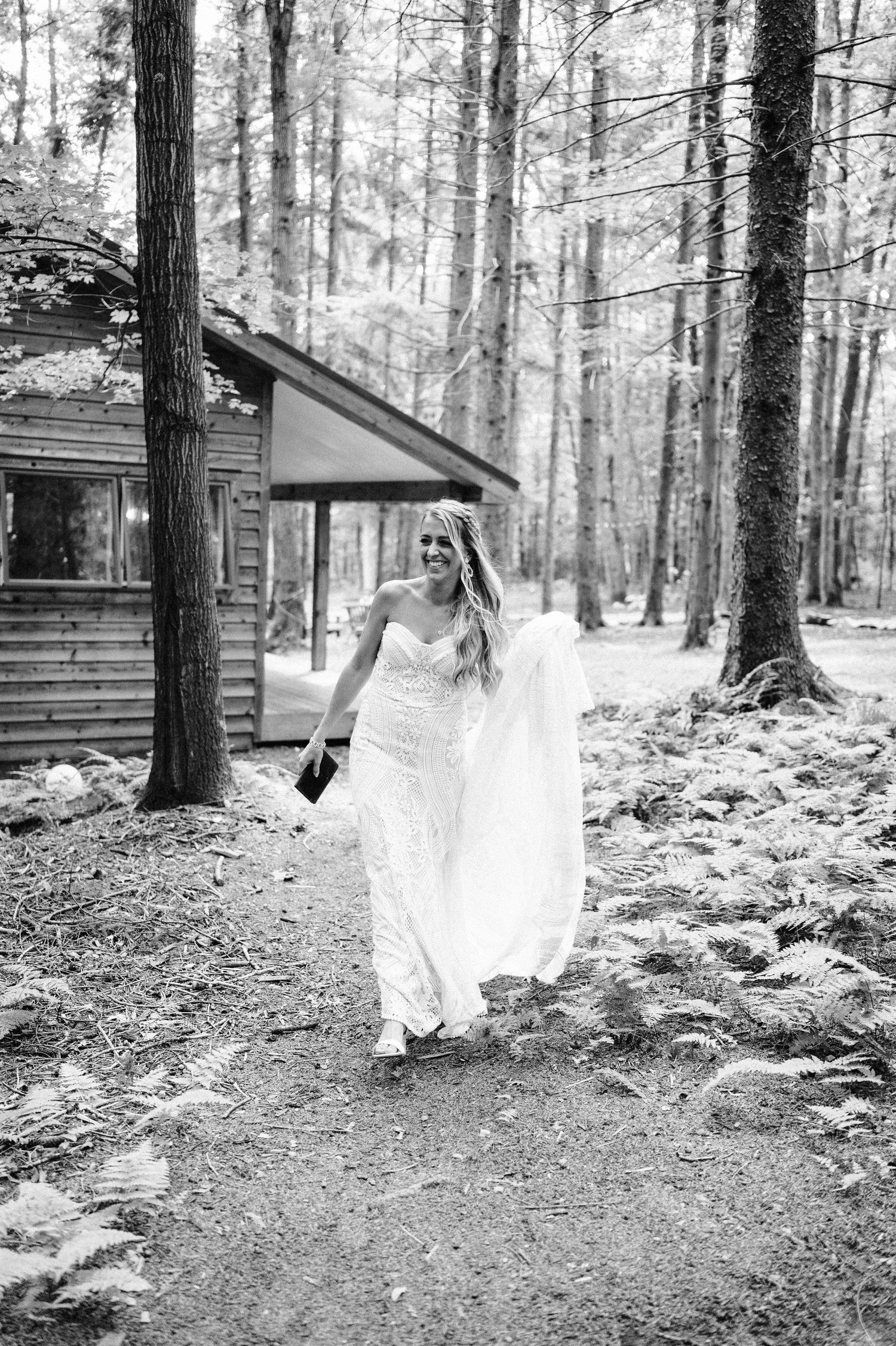 A flowing white wedding dress moves gracefully through a wooded forest setting.