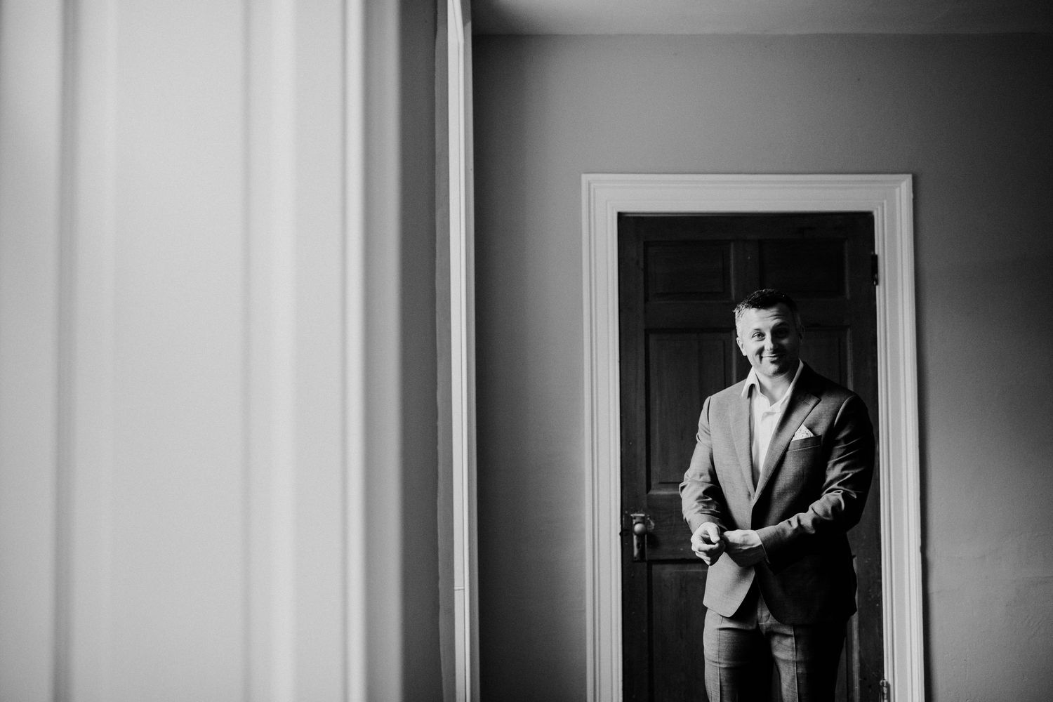 Black and white portrait of a figure standing in a doorway.