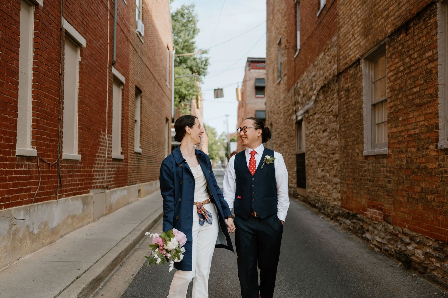 A couple walks down an alley between historic brick buildings.