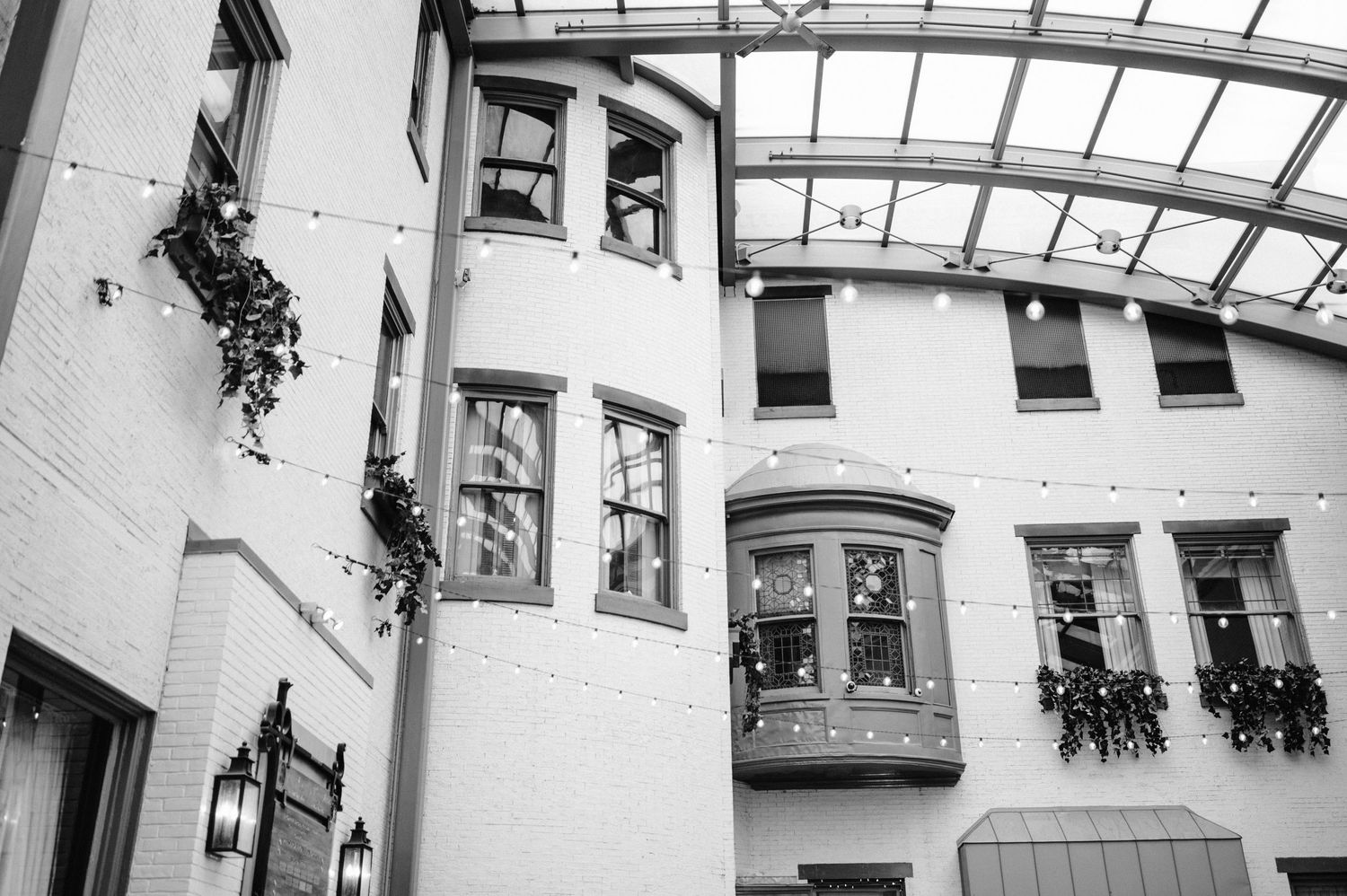 Black and white architectural photo of curved building with bay windows and glass ceiling.