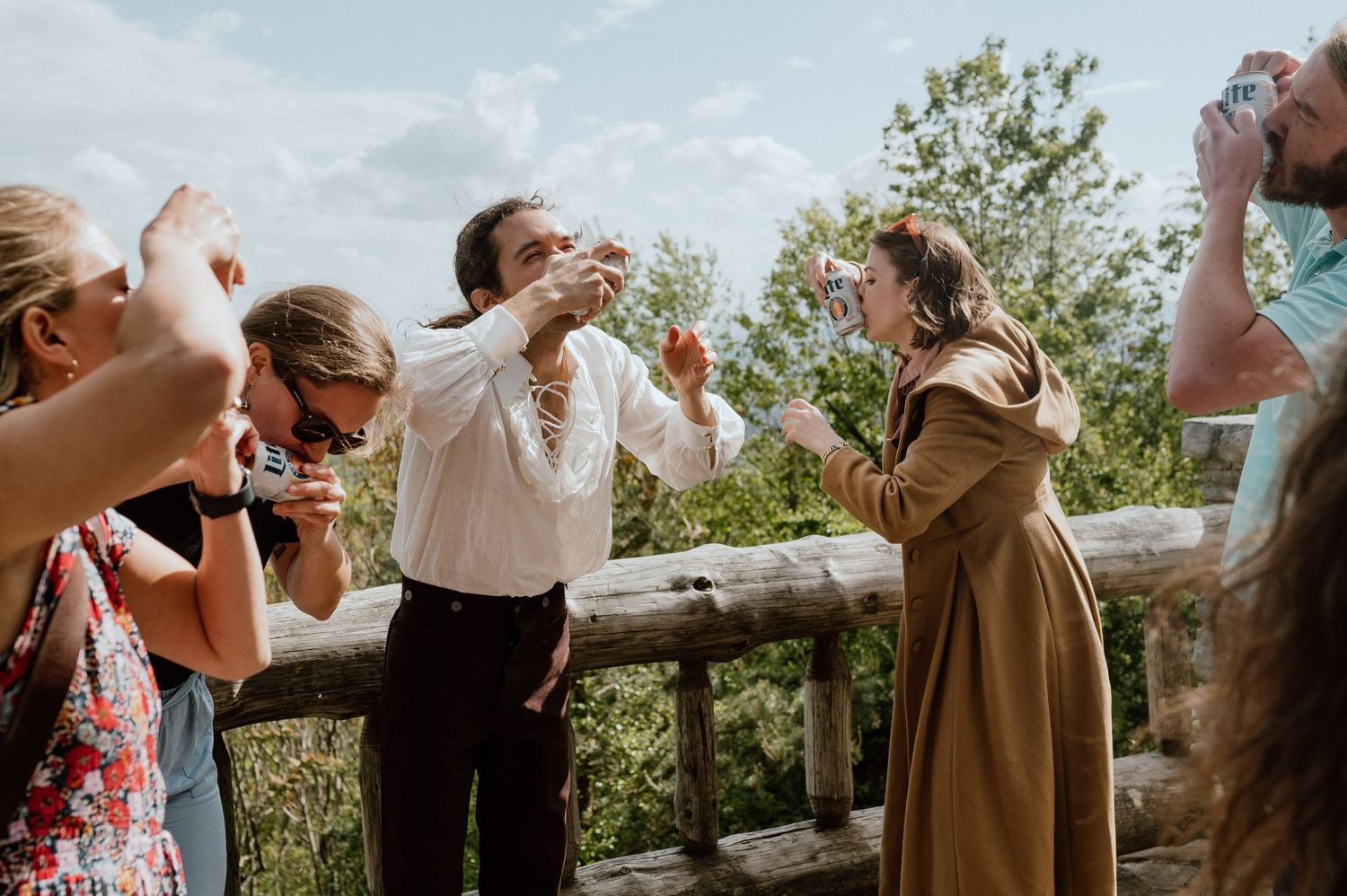 Friends celebrating and taking photos together on a mountain overlook deck.