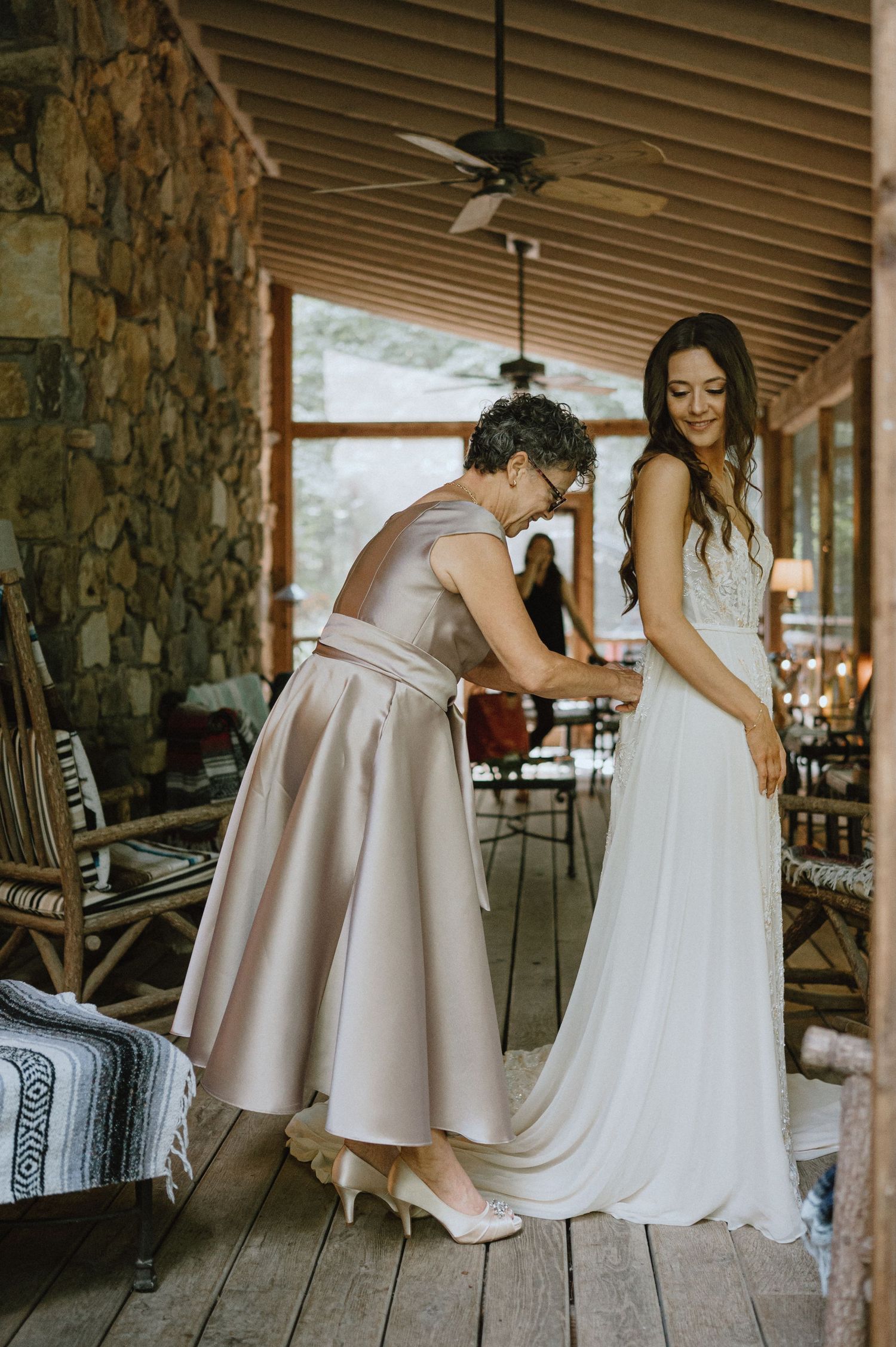 Bride and mother buttoning wedding dress