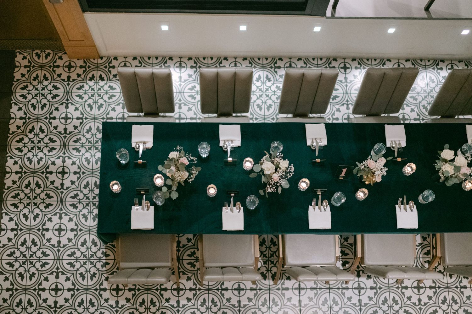 Overhead view of formal dinner table with green tablecloth and place settings.