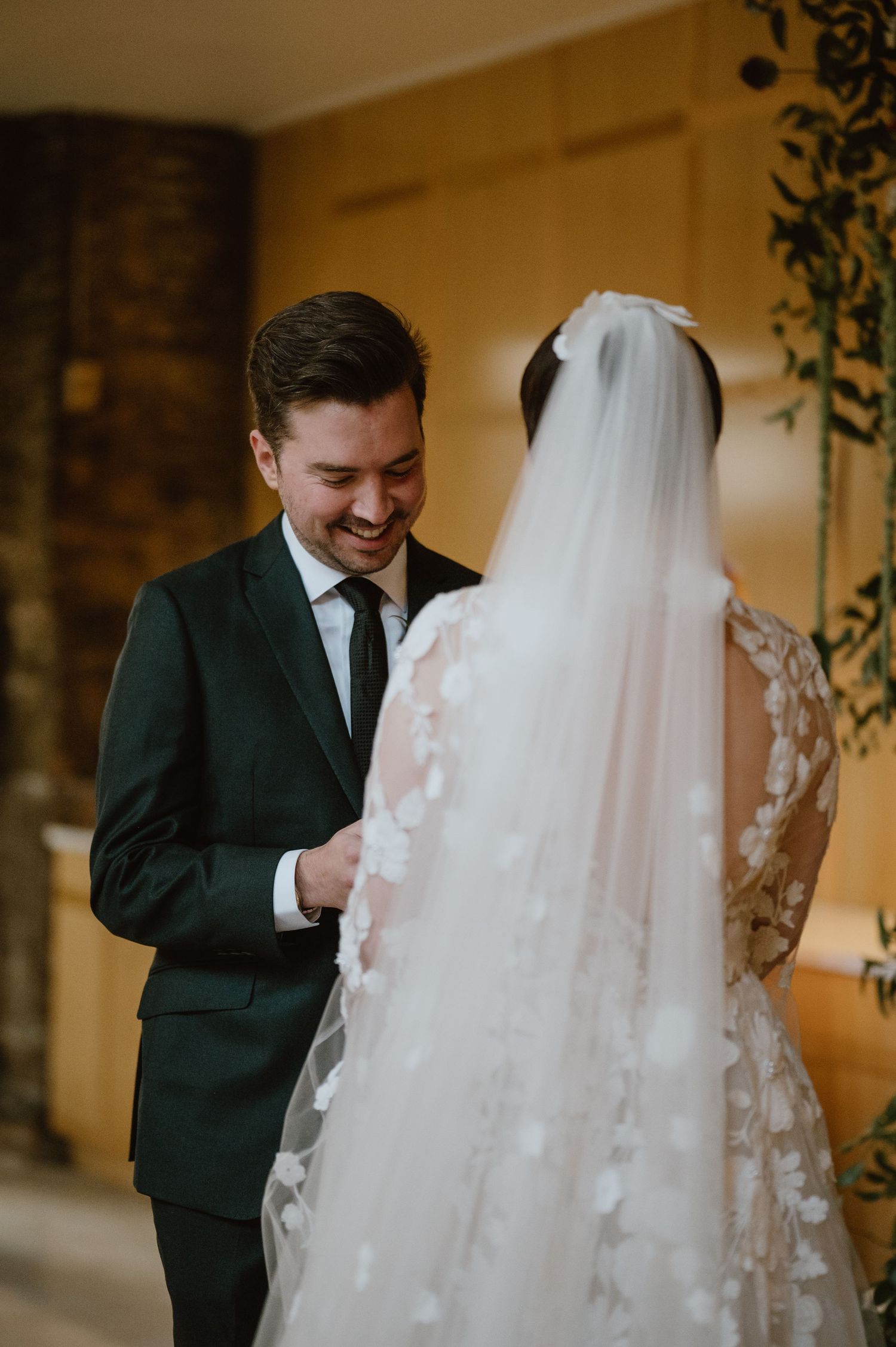 An intimate wedding moment captured in front of exposed brick walls and greenery.