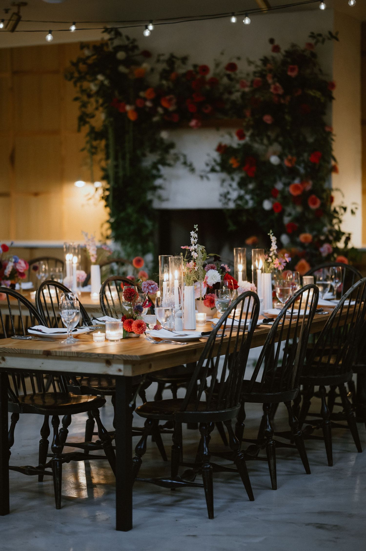 Reception table set with Windsor chairs and dramatic floral wall installation.