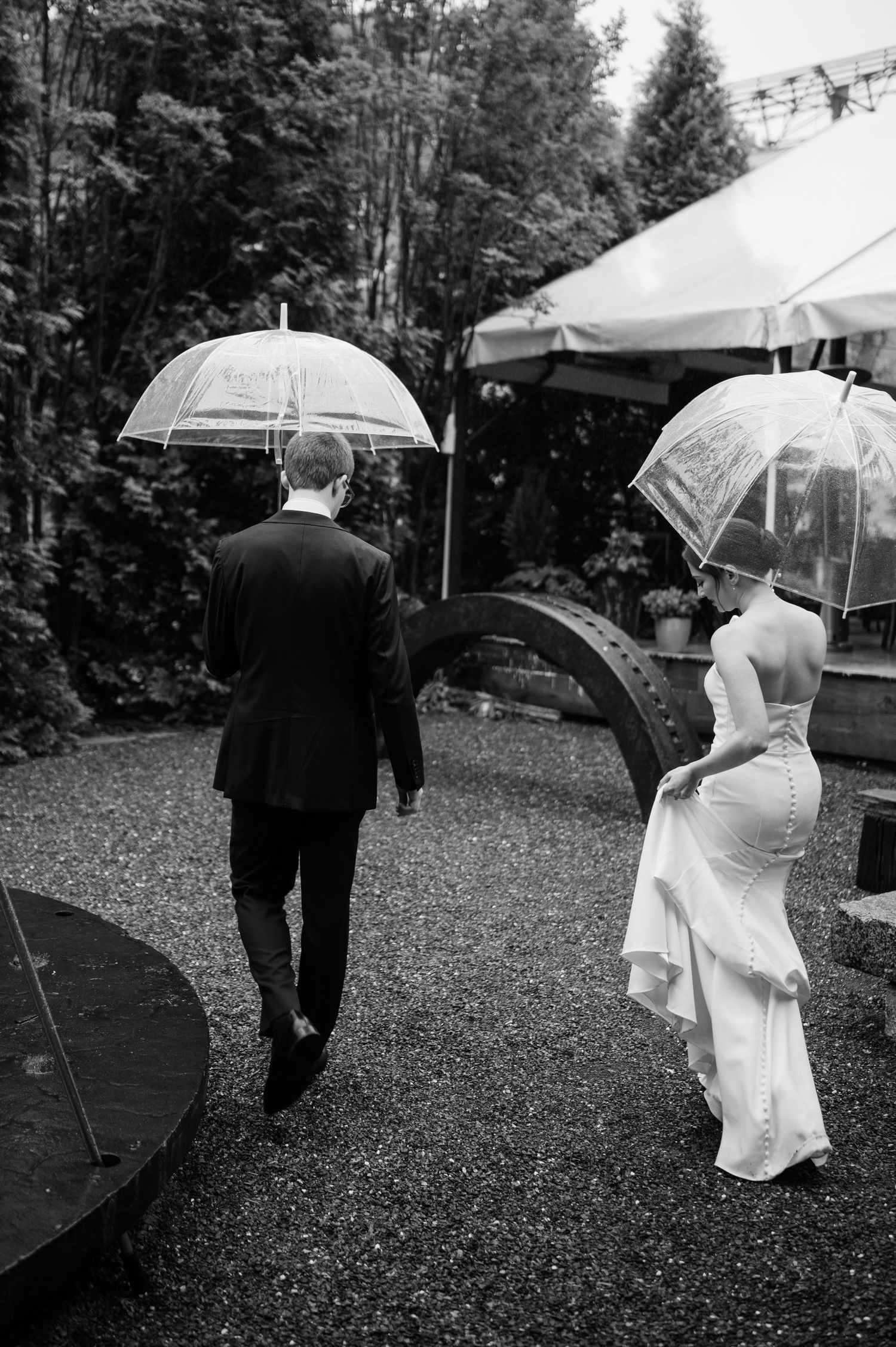 Wedding party walking with clear umbrellas on a rainy day outdoors.