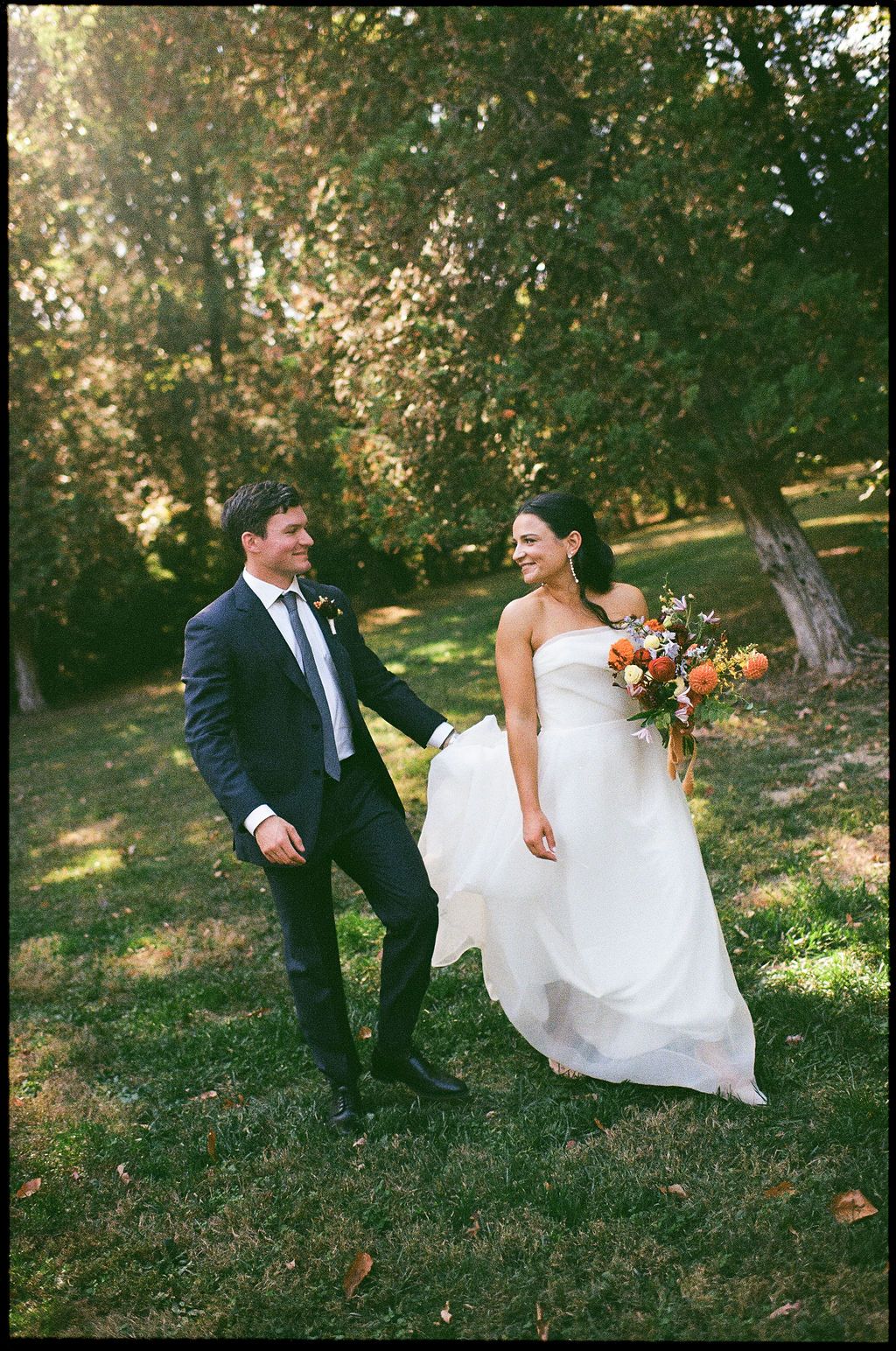 A couple dances and twirls together on a sun-dappled lawn during their wedding at Strong Mansion on Sugarloaf Mountain