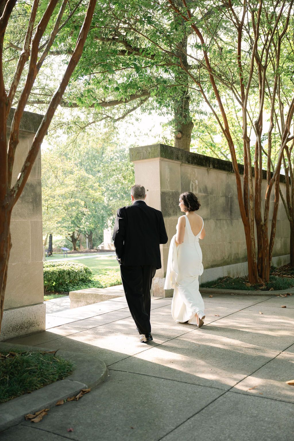 A series of five photos showing a couple walking through a covered outdoor walkway with trees visible through arches.