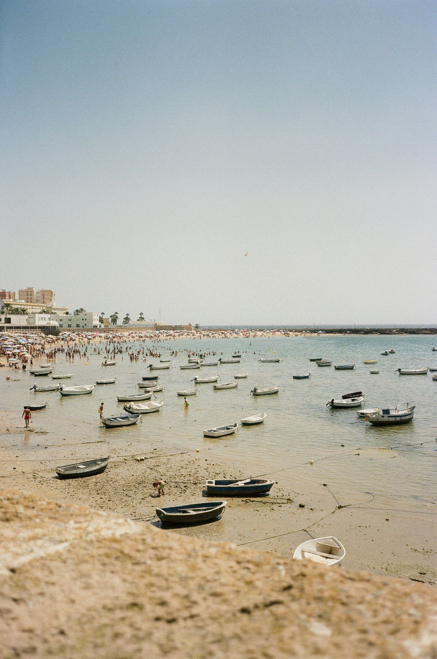 Small fishing boats scattered along a sandy beach at low tide.