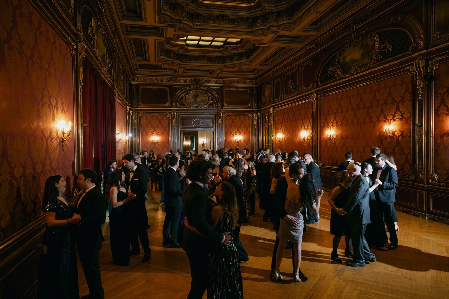 Couples dancing in a dimly lit grand ballroom with ornate walls and ceiling details at a Baltimore engineers club wedding