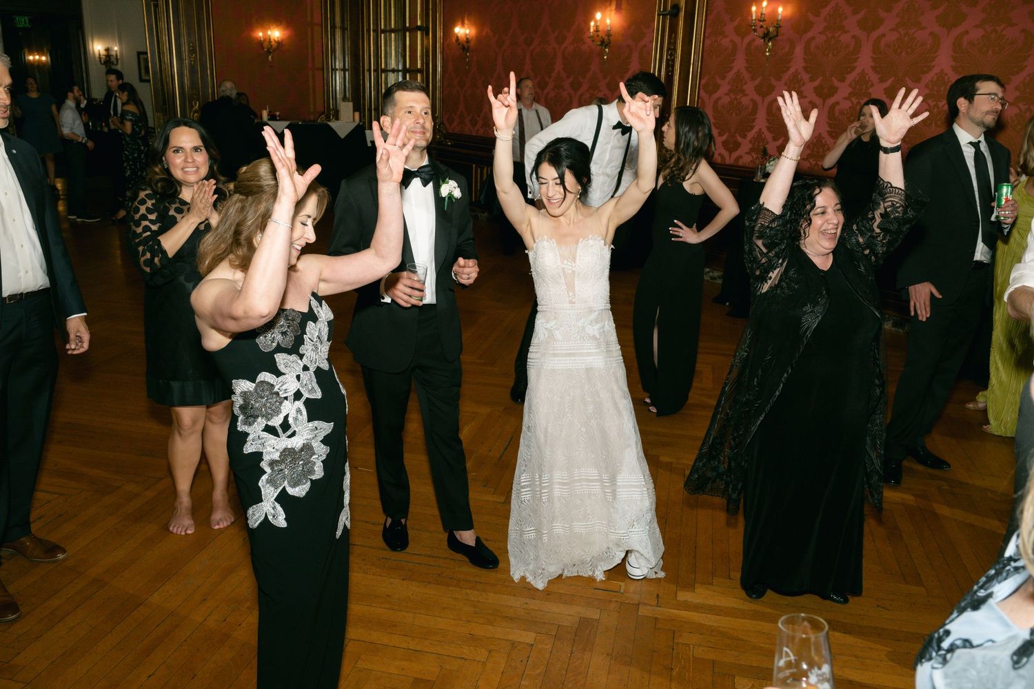 Wedding reception party with guests dancing and celebrating on a wooden dance floor.