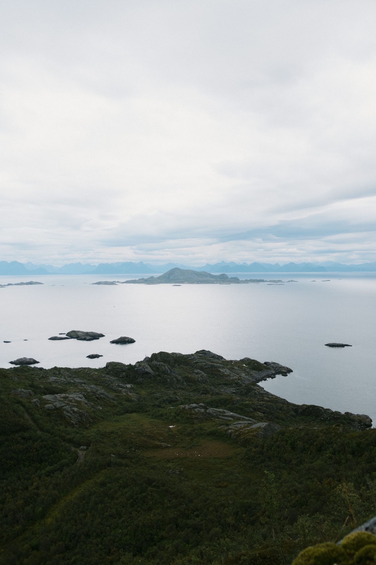 Aerial view of rugged coastline with small islands dotting the misty seascape.