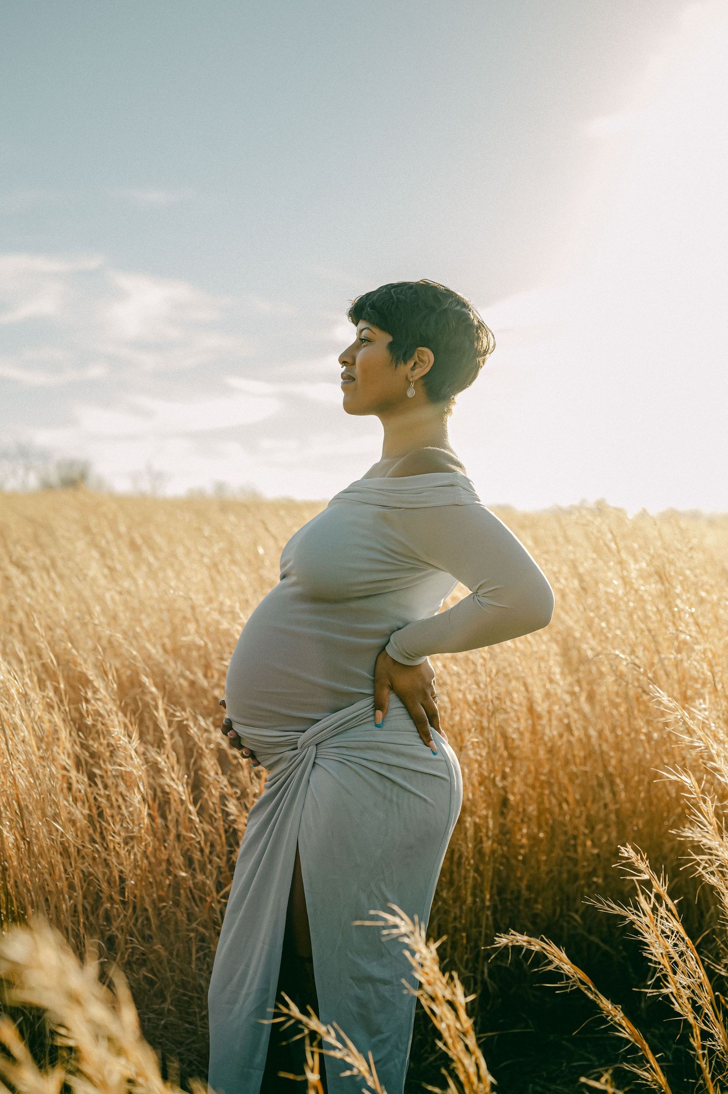 maternity photo of woman holding baby bump in field