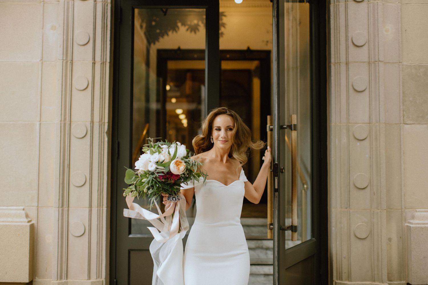bride walks out of the door of the Revival hotel in Baltimore