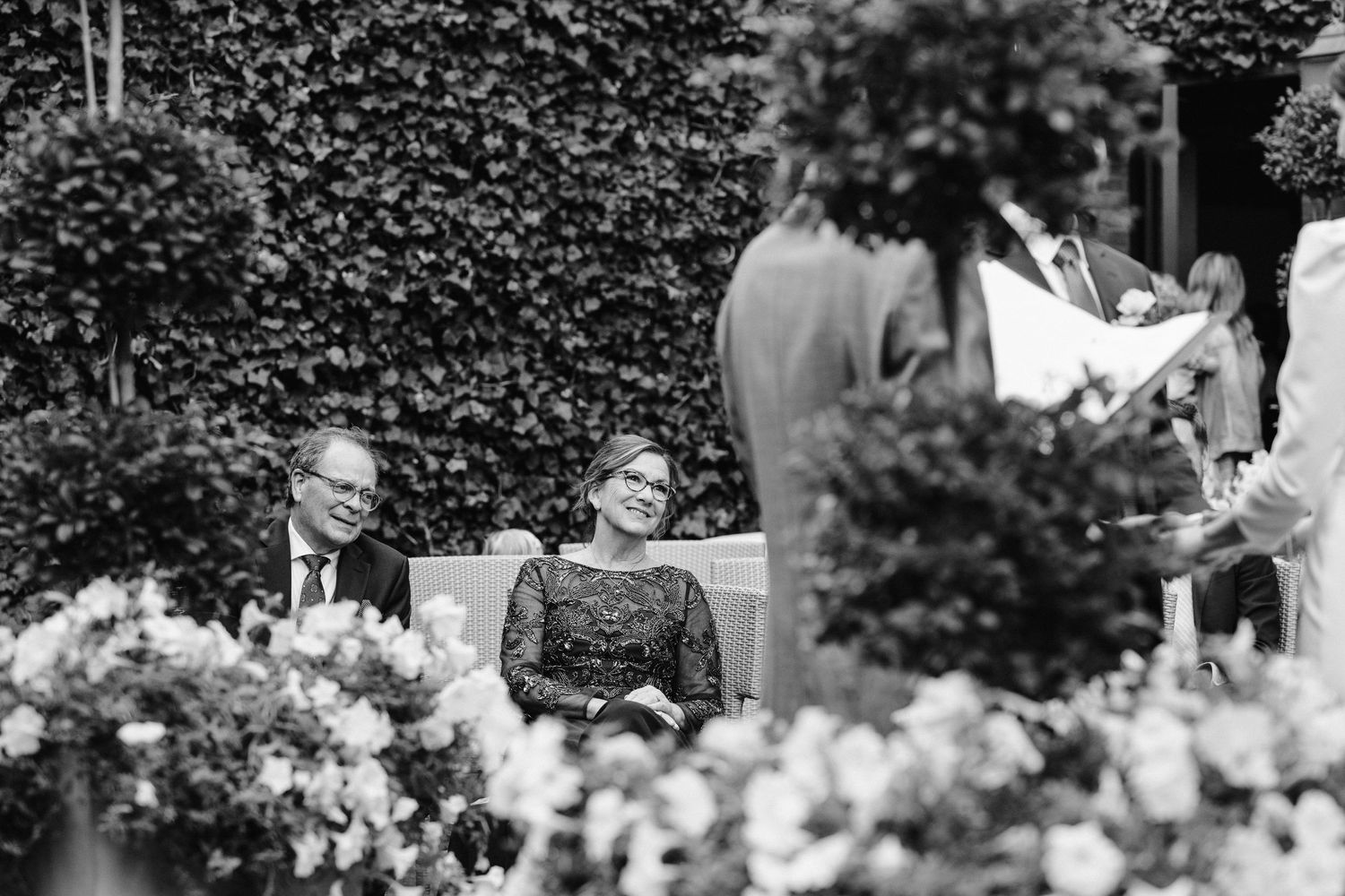 A black and white photo of wedding guests enjoying an outdoor garden reception.