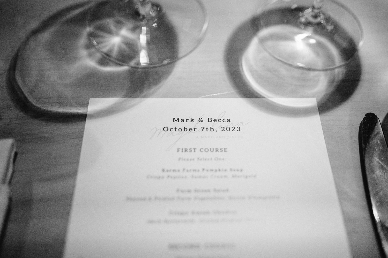 Black and white close-up of a wedding menu card with rings casting shadows.
