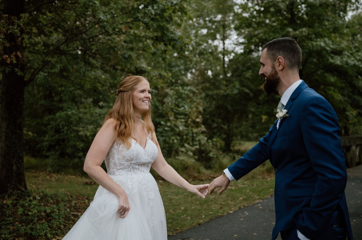 A couple sharing a joyful moment while holding hands on a forest path.