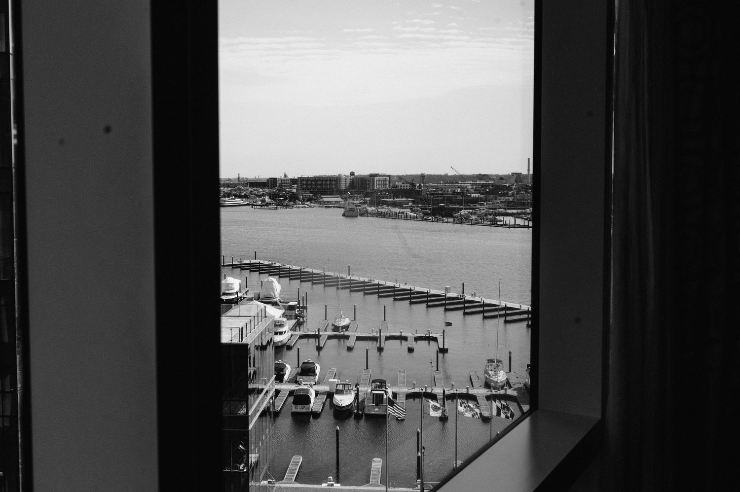 Black and white view of marina and docks through hotel window frame.