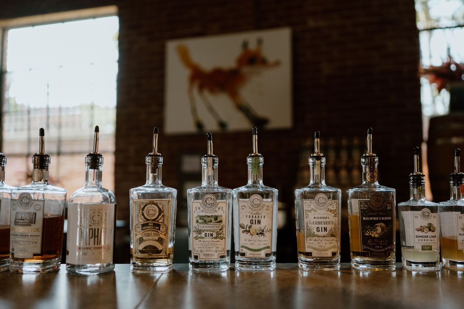 A row of craft spirit bottles lined up on a wooden bar counter.