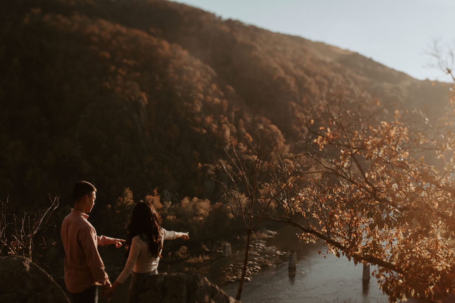 Two people admiring golden hour views from a scenic mountain overlook.