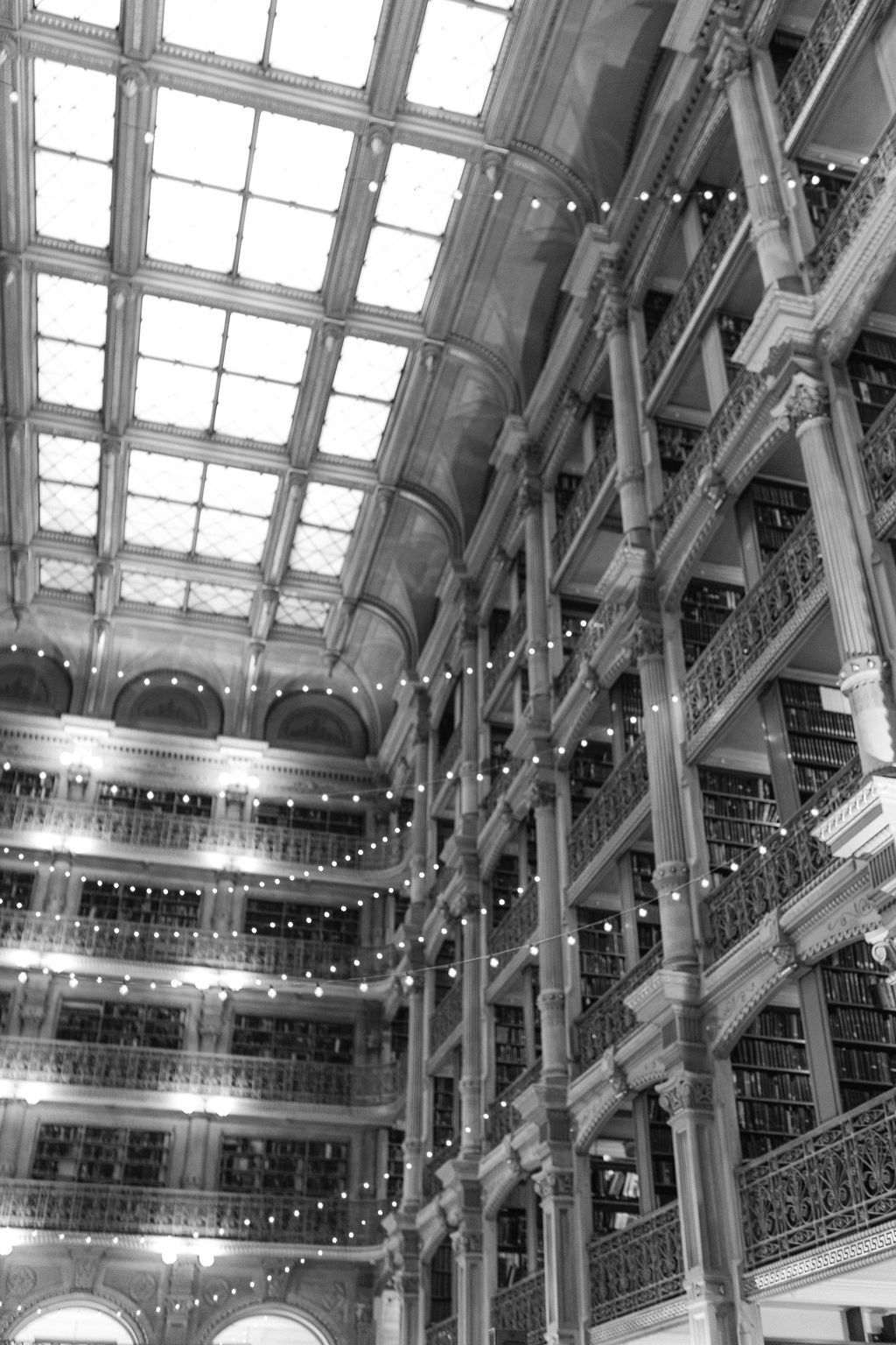 Historic library interior with multiple levels, ornate railings and a dramatic skylight ceiling.