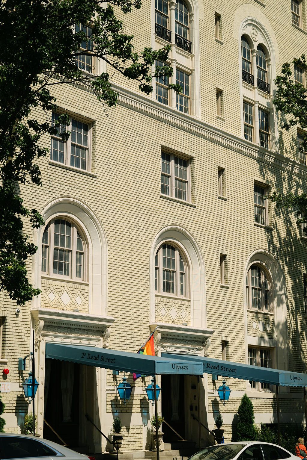 Exterior view of a cream-colored brick building with arched windows and doorways on a sunny day.