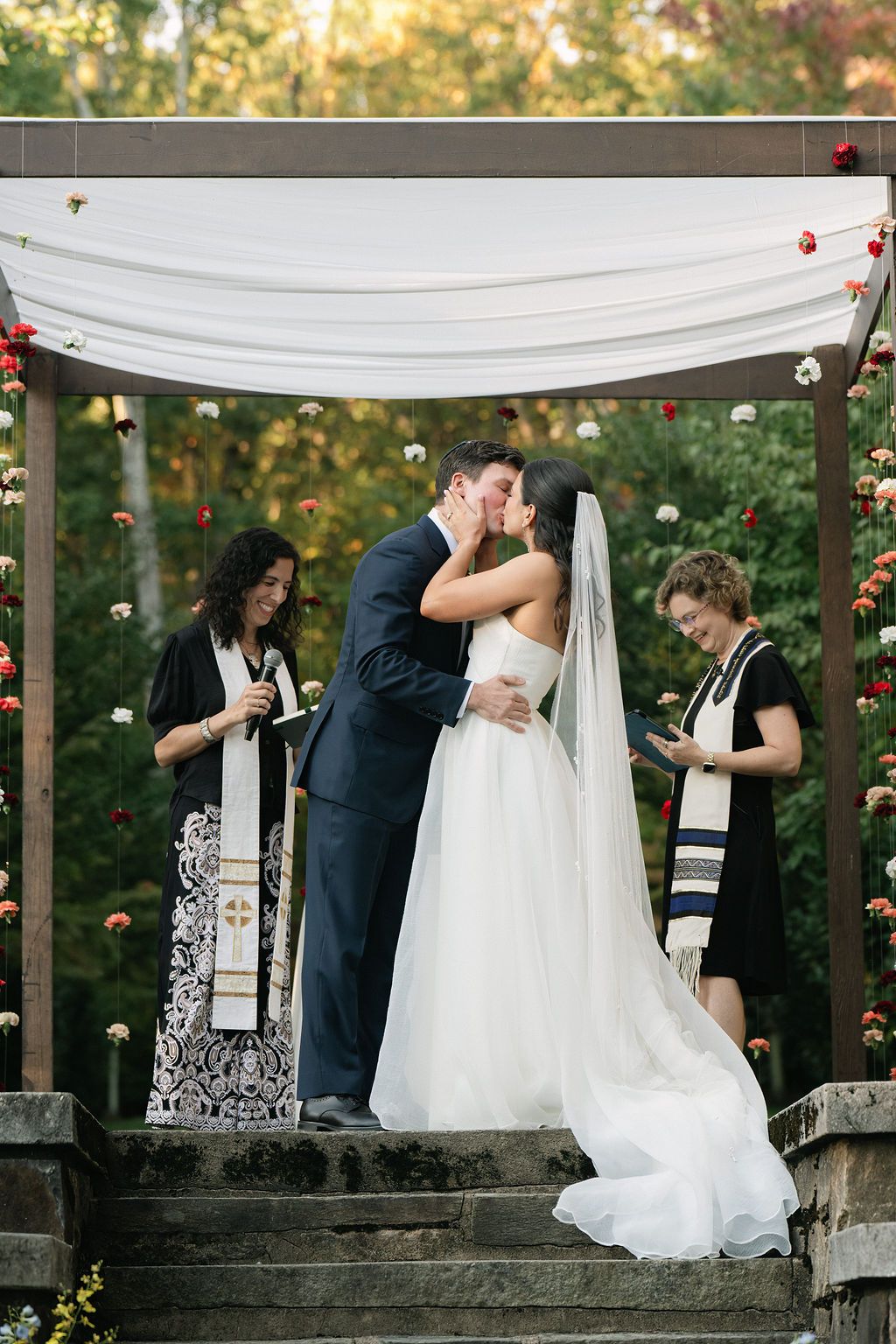 Wedding ceremony taking place under a decorated wooden arch with white fabric draping at Strong Mansion on Sugarloaf Mountain